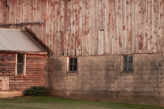 A rustic barn wall with wooden planks and brick foundation in rural setting in Ontario, Canada,