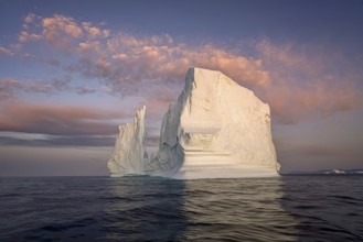 Large glaciers in the bay by the rocky shore in the light of the setting sun