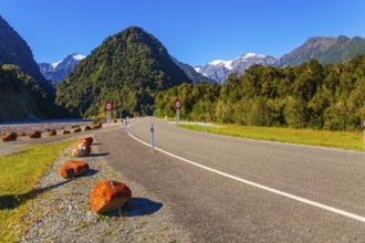 Snowy peaks of rocks are visible in the distance. Wonderful summer day. Great highway among fields,