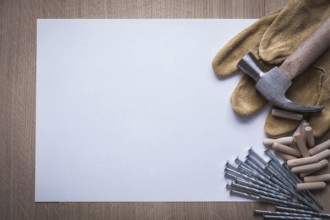 Clean sheet of paper steel nails claw hammer wooden dowel pins and leather safety gloves on wood