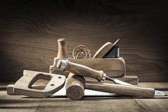 Carpenter tools woodworkers plane wooden mallet chisel handsaw on vintage wooden background