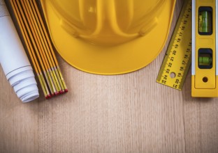 Protective helmet instruments of measurement blueprints and construction level on wooden board