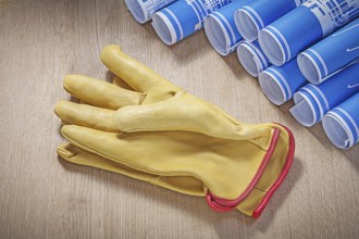 Blue construction plans leather protective gloves on wood board maintenance concept