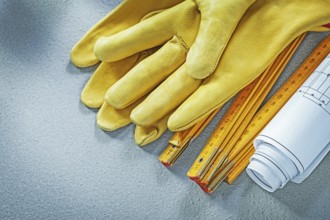 Protective gloves blueprints wooden meter on concrete background building concept