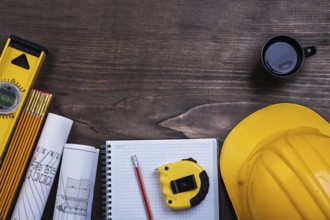 Workbook pencil cup of coffee and construction objects on wooden board maintenance concept