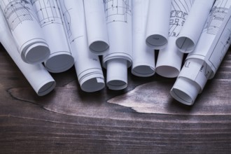 Pile of blueprint rolls on pine wooden vintage board maintenance concept
