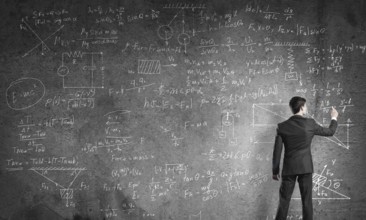 Man in suit standing with back and drawing physics formulas