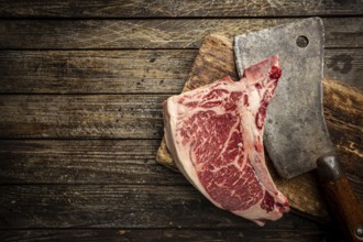 Raw fresh meat T-bone beef Steak and butcher knife on wooden background, top view