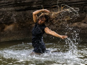 Middle-aged woman dancing and throwing water in the air, Maioris beach, llucmajor, Majorca,