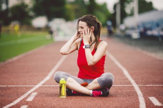 Theme healthy lifestyle, sports music. beautiful young Caucasian woman rests sitting treadmill