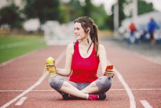 Beautiful fitneß girl uses smartphone at stadium after workout. Sports and healthy. Sport woman use