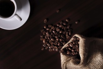Coffee still life with cup, coffee beans in bag. Low key light