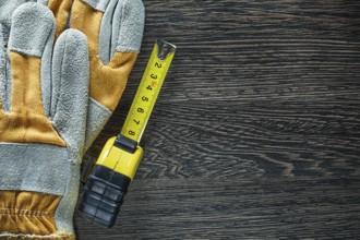 Rolled tape measure safety gloves on wood board
