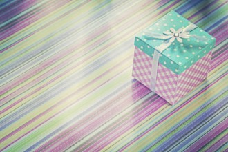 Wrapped present box on stripy fabric background holidays concept