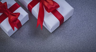 White giftboxes with red knots on grey surface holidays concept