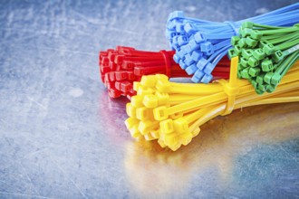 Multicolored plastic tying cables on metallic background construction concept