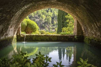 Tranquil, arched tunnel with views of water and trees in the background, Jardines de Alfabia