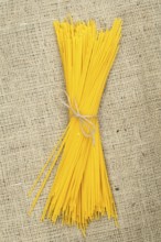 Bundle of spaghetti on burlap brown background
