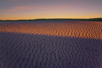 Orange sunset in the desert. Mesquite Flat Sand Dunes, California. The gentle slopes of the sand