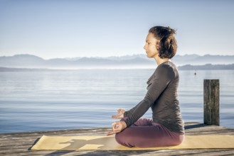 A pretty woman doing yoga at the lake