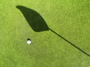 Golf ball on the green, shadow of a flag on a green, golf course