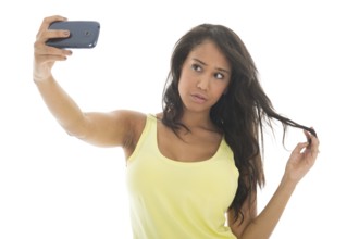 Young attractive black woman is taking a selfie with her cellphone isolated over white background