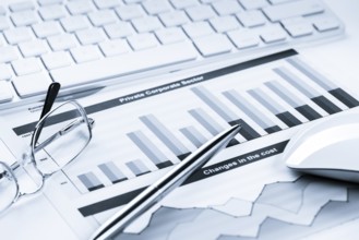 Business workplace with keyboard glasses and financial documents on table