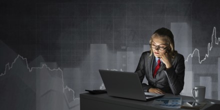 Attractive young businesswoman in glasses sitting at office desk and working at laptop. Female