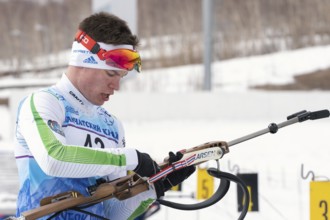 Biathlete reloads rifle before rifle shooting on shooting range. Sportsman biathlete Zlobin