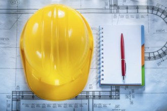 Protective building helmet notebook pen on blueprint