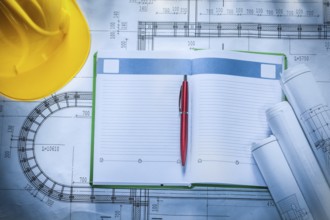 Pen hard hat construction drawings notepad on blueprint