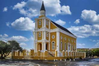 A view of a yellow church in willemstad on curacao with blue sky and nice clouds