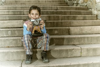 Child with vintage camera. Exterior stairs