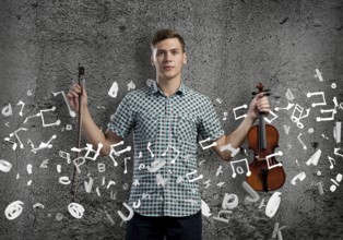 Young handsome guy on cement background with violin