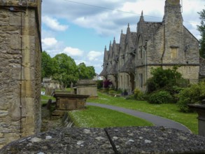 Charming cotswold stone houses stand alongside a serene cemetery, showcasing the timeless beauty of