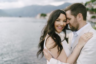 Man hugs smiling woman by the sea. Portrait.