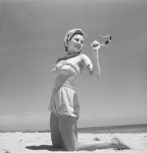 1940s summer. A young woman by the sea is getting a nice suntan. She is wearing a typical 1940s