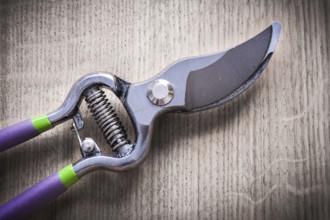 Sharp metal pruning shears on wooden board agriculture concept