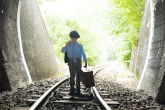Child walking on railway road with vintage siutcase