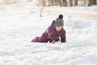 Boy playing with snowplow toy. Cold winter day