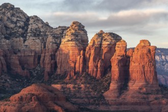 Towering red rock formations in a desert landscape with warm sunset lighting casting long shadows