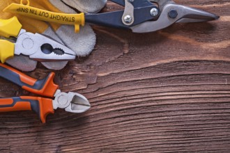 Nippers pliers wire-cutter and construction glove on wood board maintenance concept