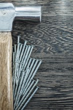Heap of construction nails claw hammer on wooden board