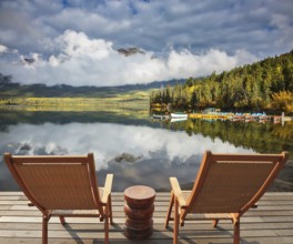 Pyramid Mountain reflected in Pyramid Lake. Two comfortable wooden sun beds for tourists,