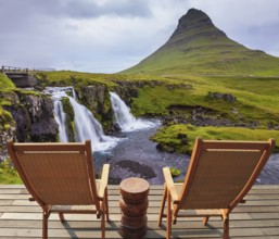 Threaded full-flowing waterfall Kirkyufell Foss on the grassy mountains. Deck chairs on the wooden