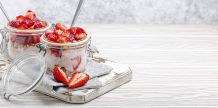 Parfait with Fresh Strawberries, Yoghurt and Crunchy Granola in Transparent Glass Mason Jars on