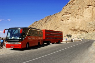 On the way to Erfound, A red coach stops next to a rocky road under a blue sky, Near Fes, Northern