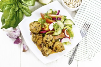 Minced meatballs with spinach, oatmeal and green onions in tomato sauce, vegetable salad in a
