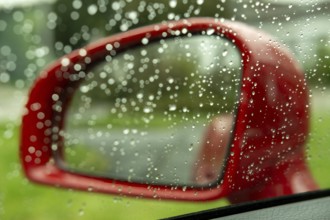 Red exterior mirror of a car in the rain