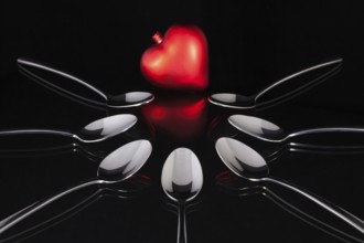 Teaspoons and love symbol on the black glass desk